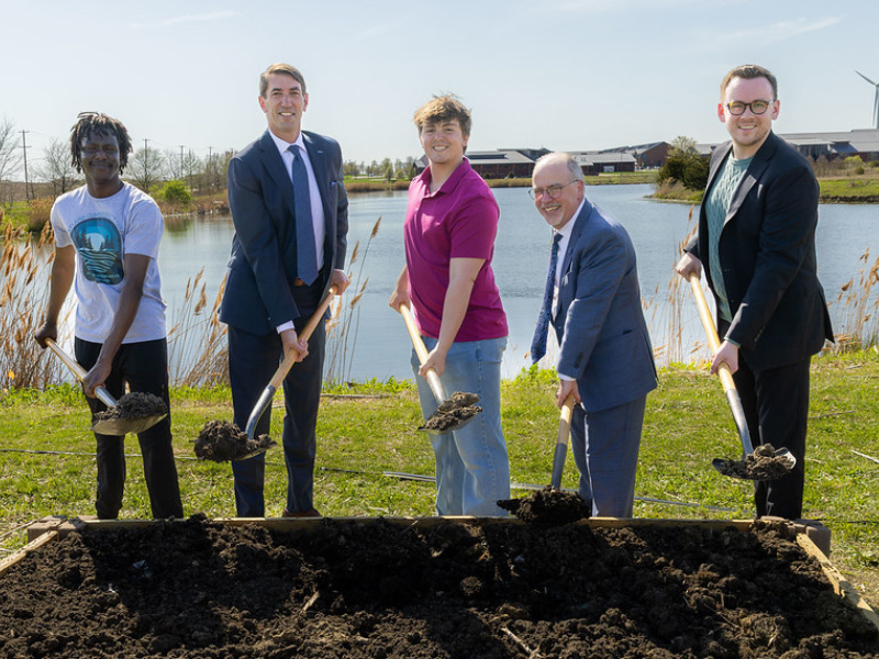 A photo of a group of people holding shovels of dirt
