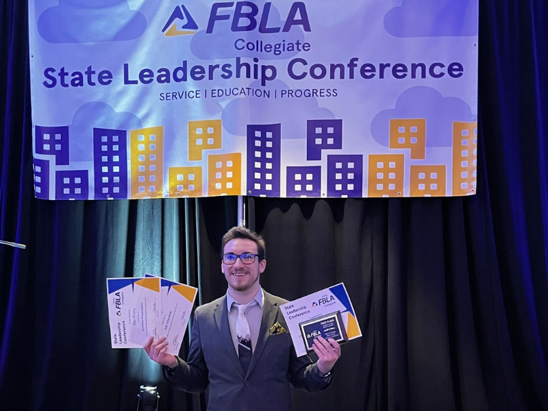 A photo of Gage Codding holding his awards on stage