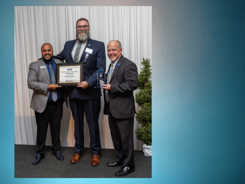 A picture of 3 gentleman, one of them with an award