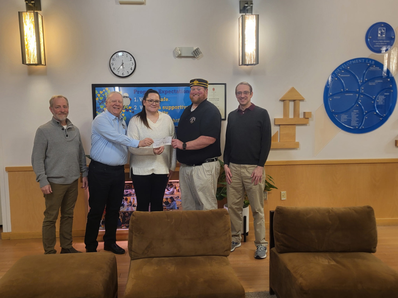 A picture of a group of men presenting a check to a woman.