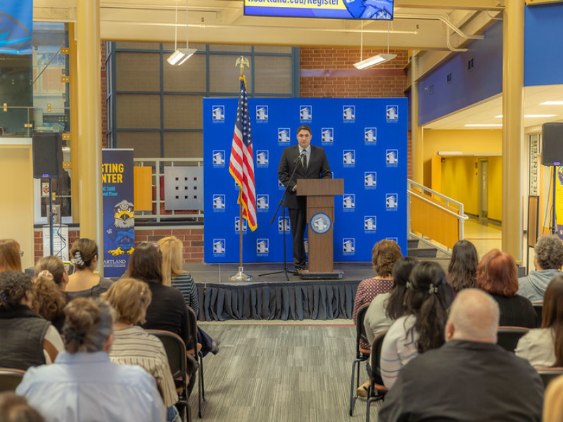 A photo of a man in front of a Heartland background speaking to a crowd