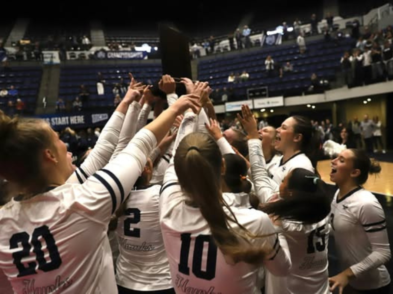 Photo of the volleyball team hoisting the championship plaque overhead