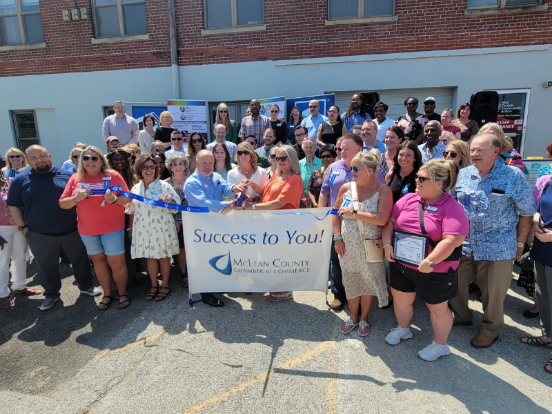 Group photo of people holding a banner in front of a building